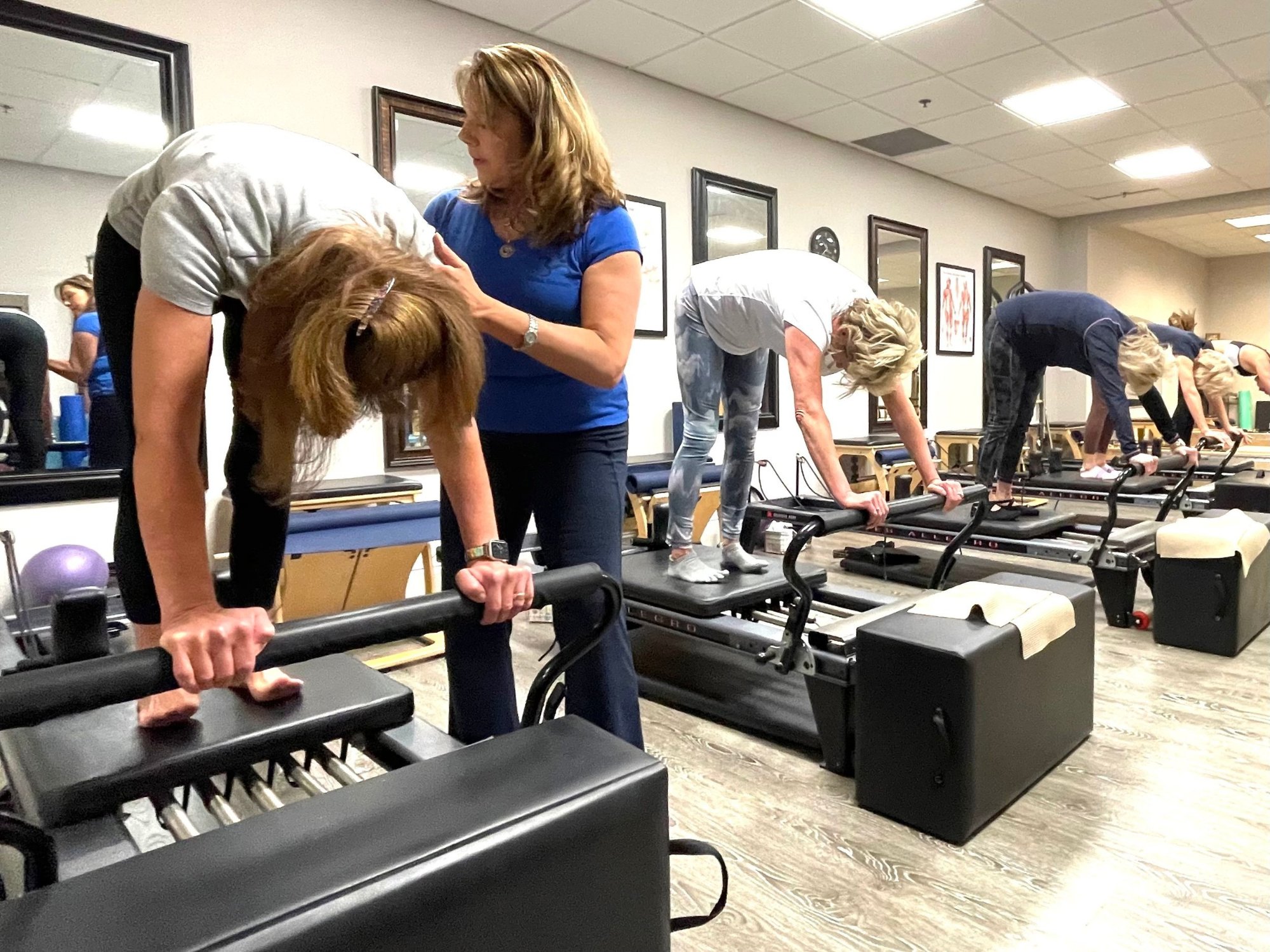 Terri gives hands-on cues to a client during a small-group reformer class
